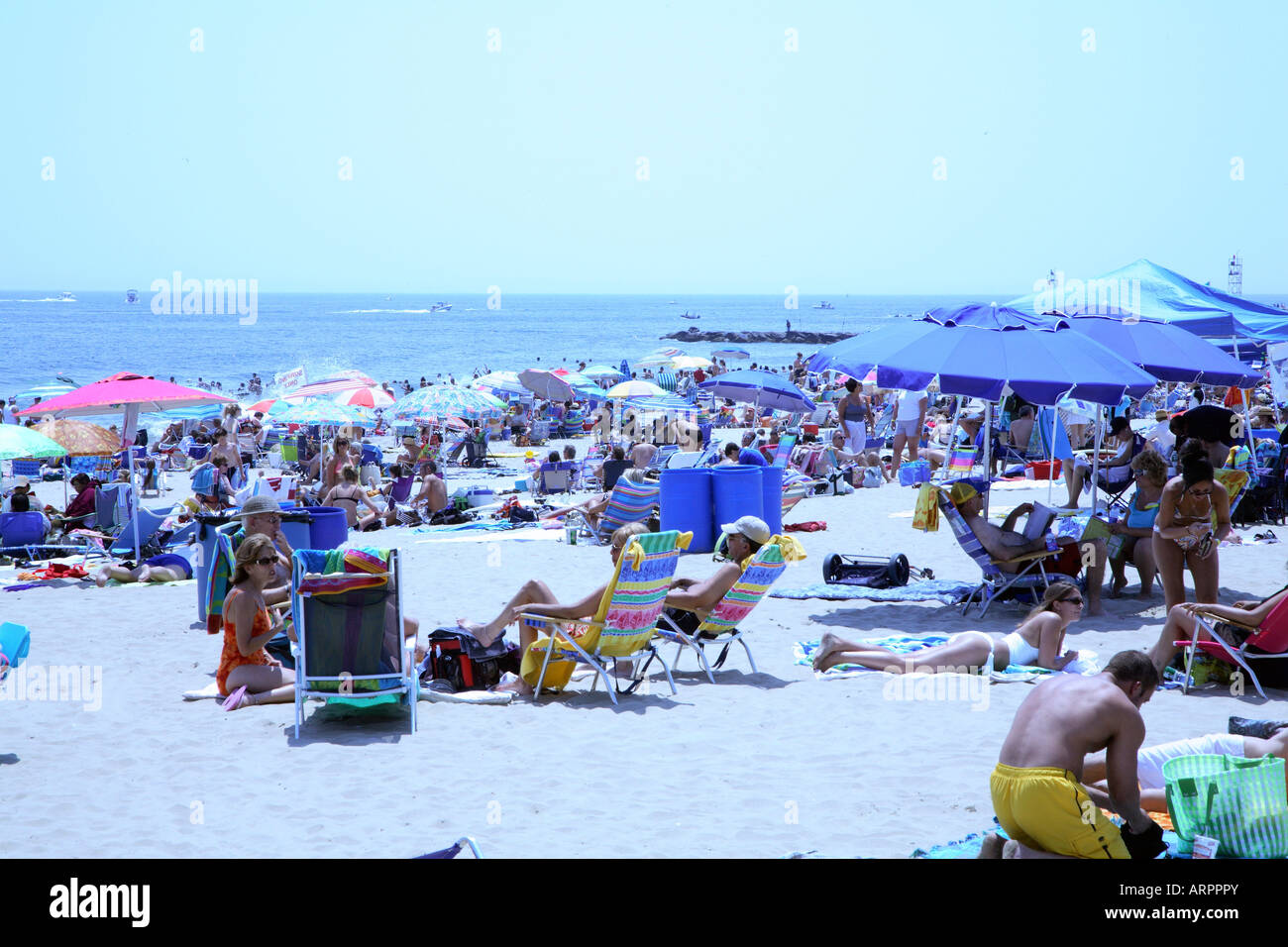 Mass of people with colorful beach umbrellas, chairs and towels on sandy beach at New Jersey shore. Stock Photo