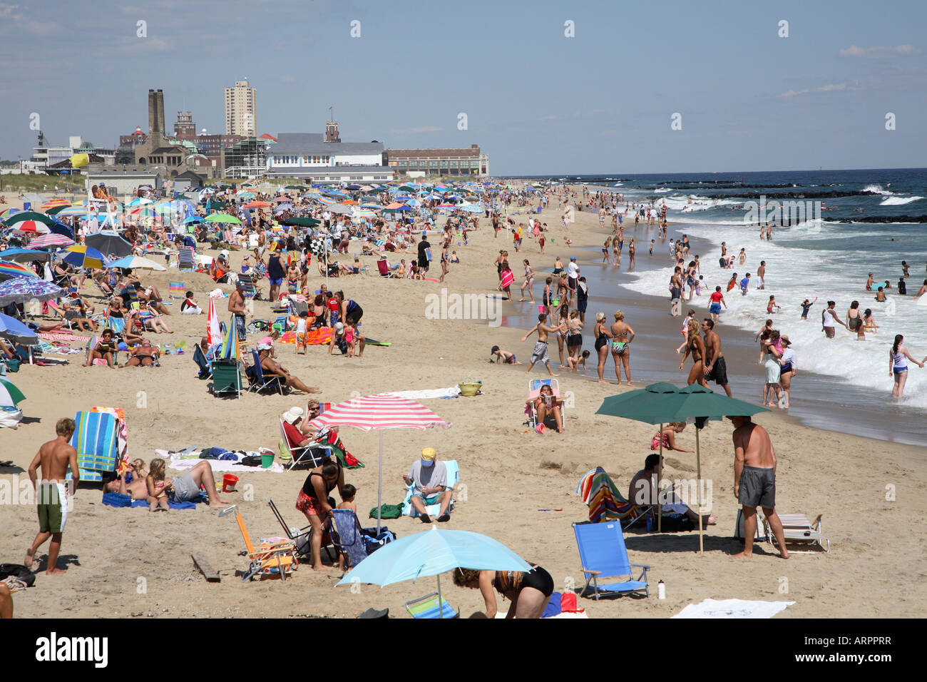 Along the surfline of a jersey shore beach with people walking, standing and splashing in the shallows. Stock Photo