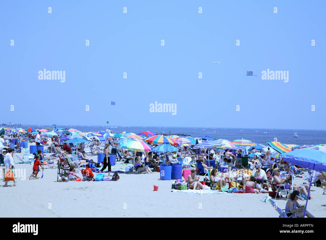 Mass of people with colorful beach umbrellas, chairs and towels on sandy beach at jersey shore. Stock Photo