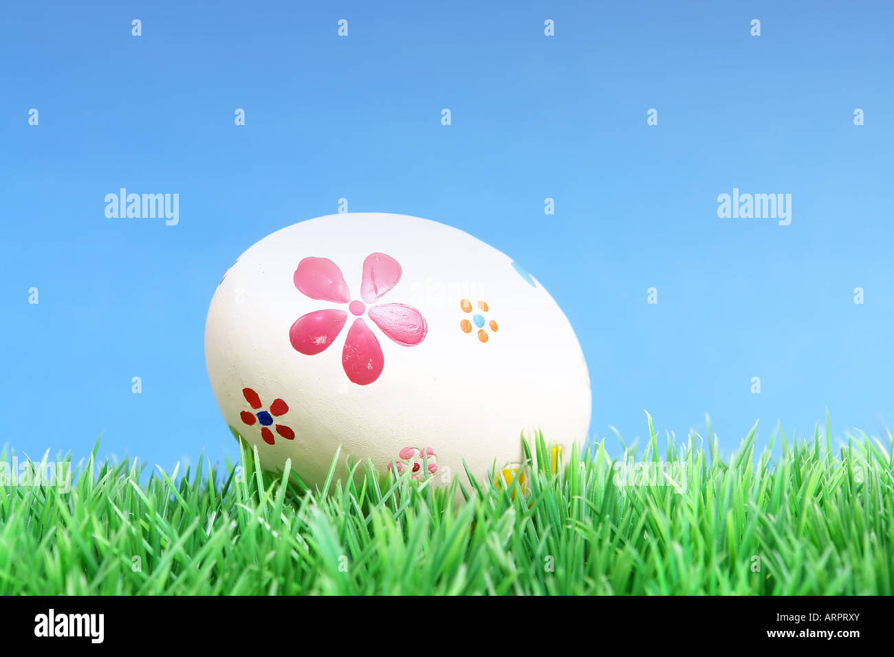 Painted easter egg laying in grass over blue sky Stock Photo - Alamy