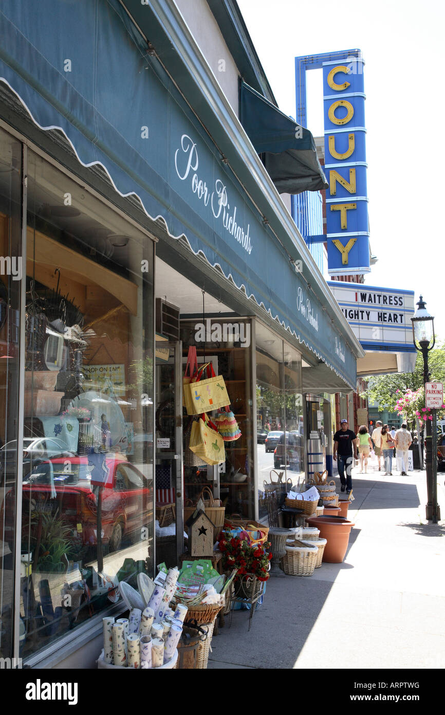 Outside of variety shop with wares arranged in baskets along the brick sidewalk below large fabric sign with shop name. Stock Photo