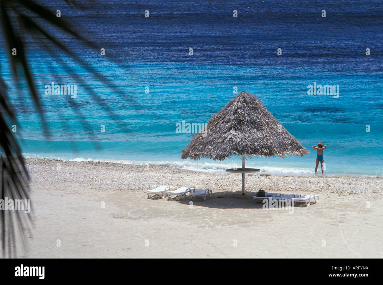 Thatched beach shelter and woman putting on snorkeling gear Sunset