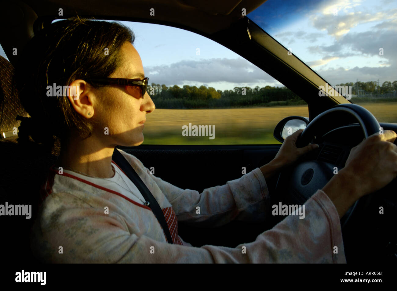 Woman wearing sunglasses while driving home in her car. Stock Photo