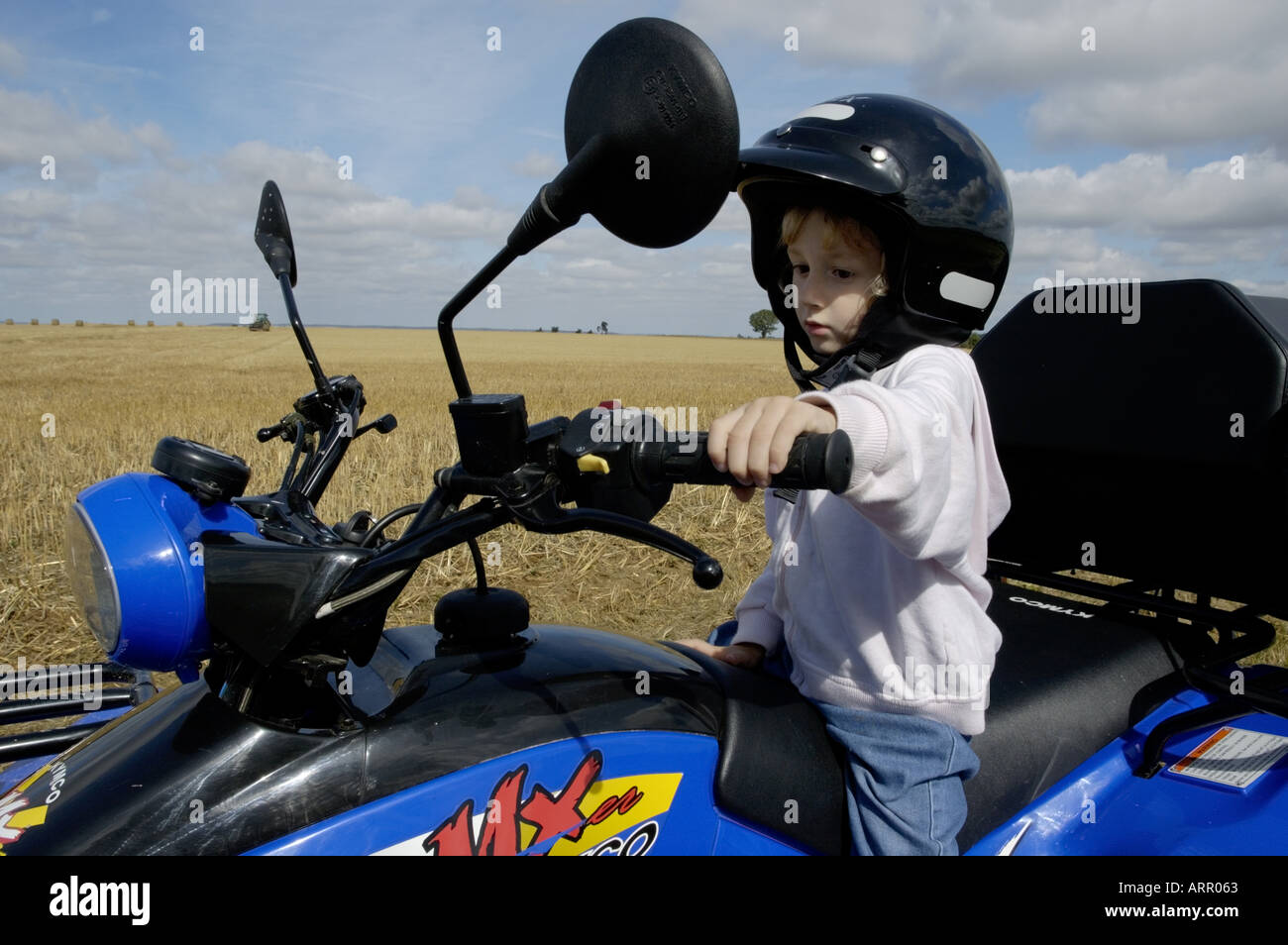 Four year old girl pretending to drive a quadbike, France. Stock Photo