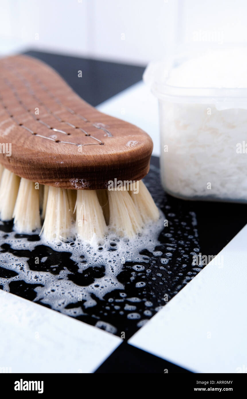 Cleaning with a traditional wooden scrubbing brush using organic soap flakes. Stock Photo
