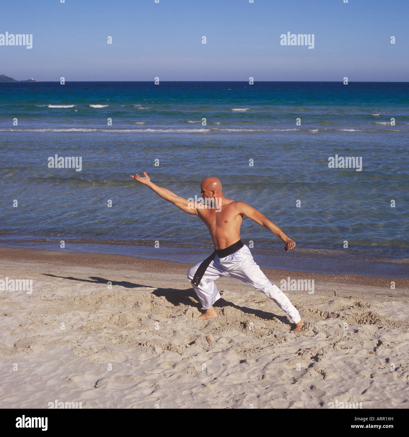 Professional Tai Chi and Kong Fu instructor undertaking workout on beach in Mallorca, Balearic Islands, Spain. Stock Photo