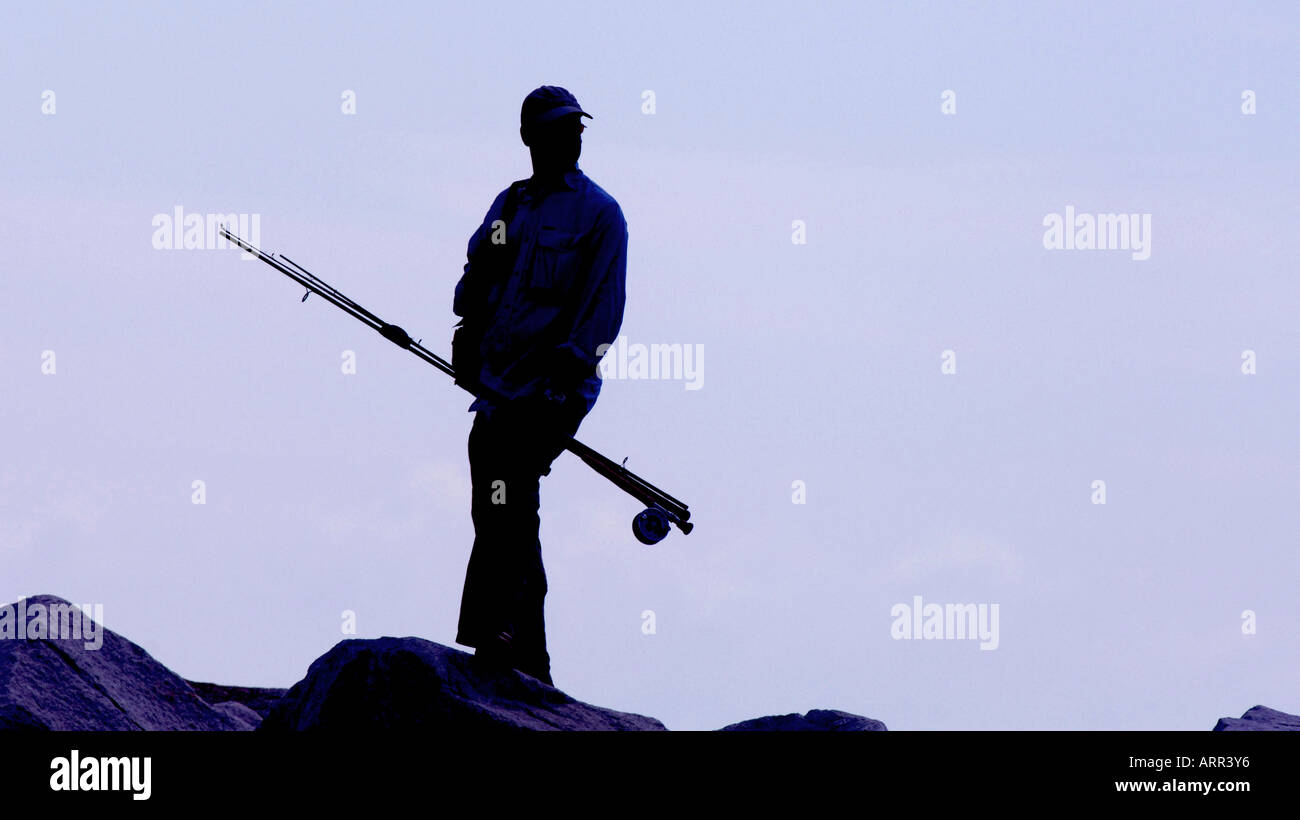 Angler holding fishing rod silhouetted against a mauve morning sky. Picture by Jim Holden. Stock Photo