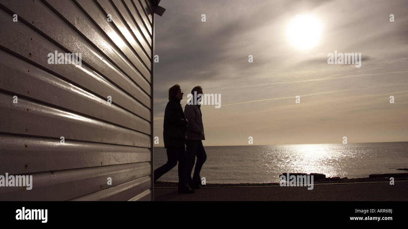 A couple walk past a beach hut on Felixstowe seafront on a winter's afternoon. Stock Photo