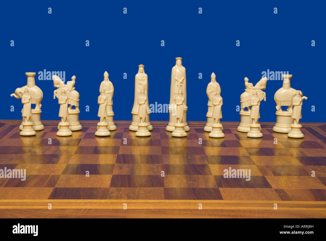 Chess set against a blue background shows the ivory colored team ready for competition Stock Photo