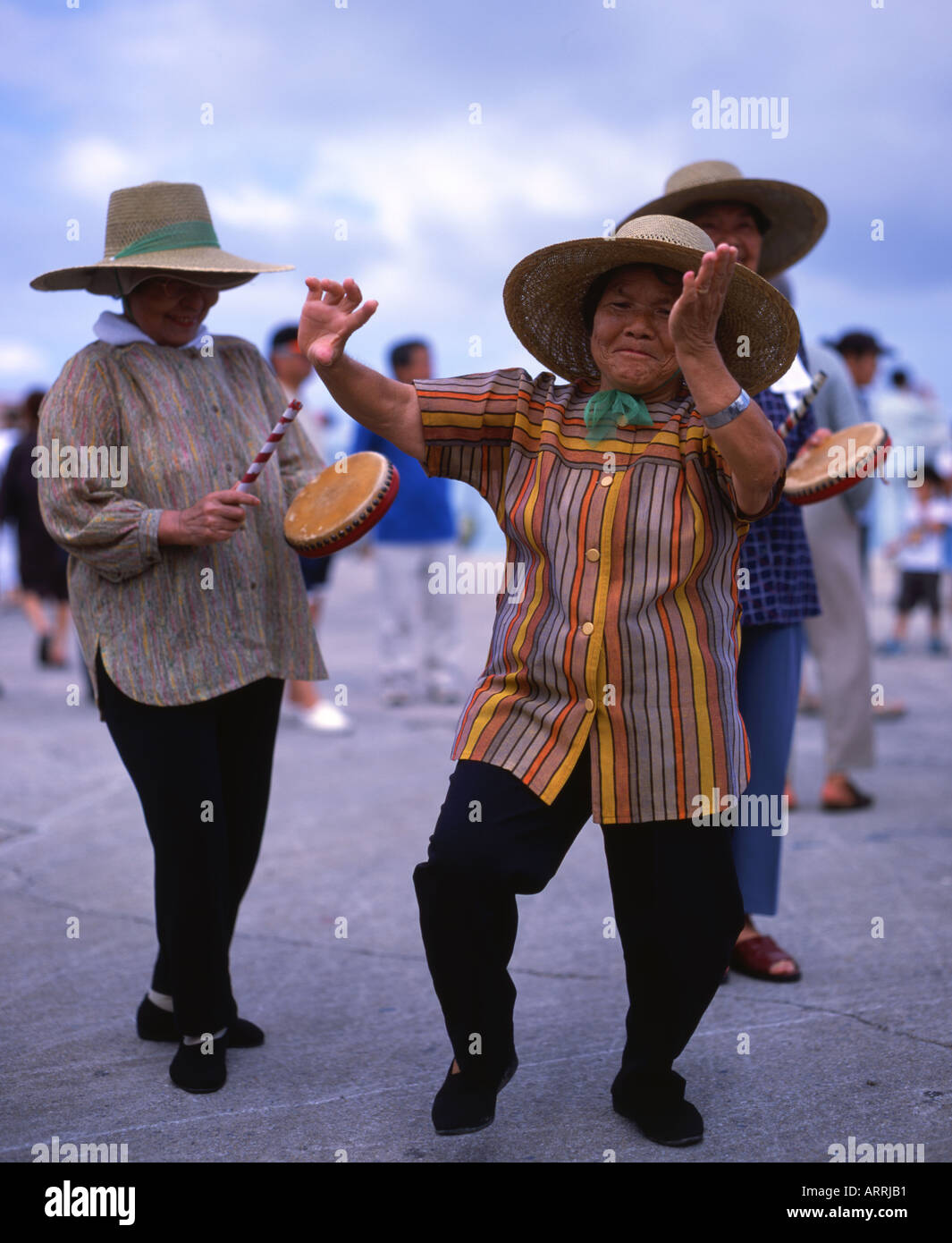 Elderly Okinawan women dance to urge on the competitors at the local dragon boat races Stock Photo