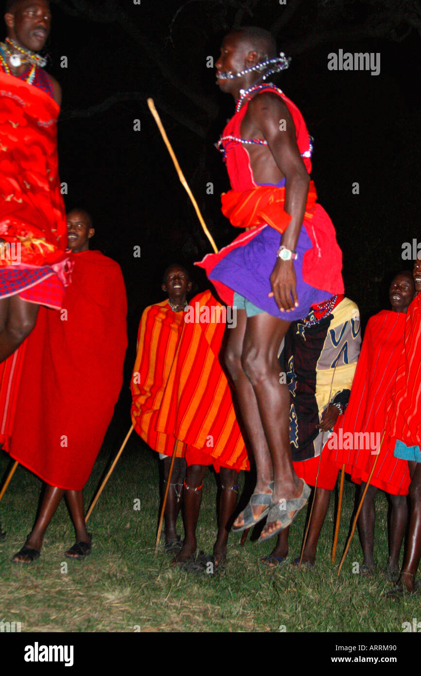 Masai warriors jump during dancing at night on safari in Base Camp Masai Mara national nature reserve Kenya East Africa Stock Photo