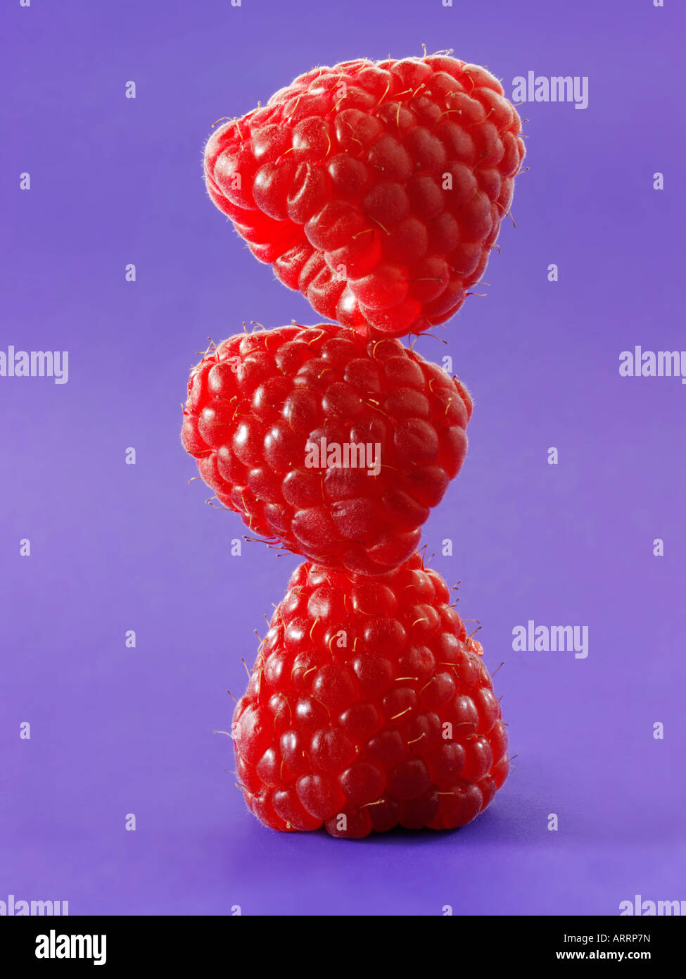 close up of a stylised stack of raspberries standing onto of each other - concept creative photo Stock Photo
