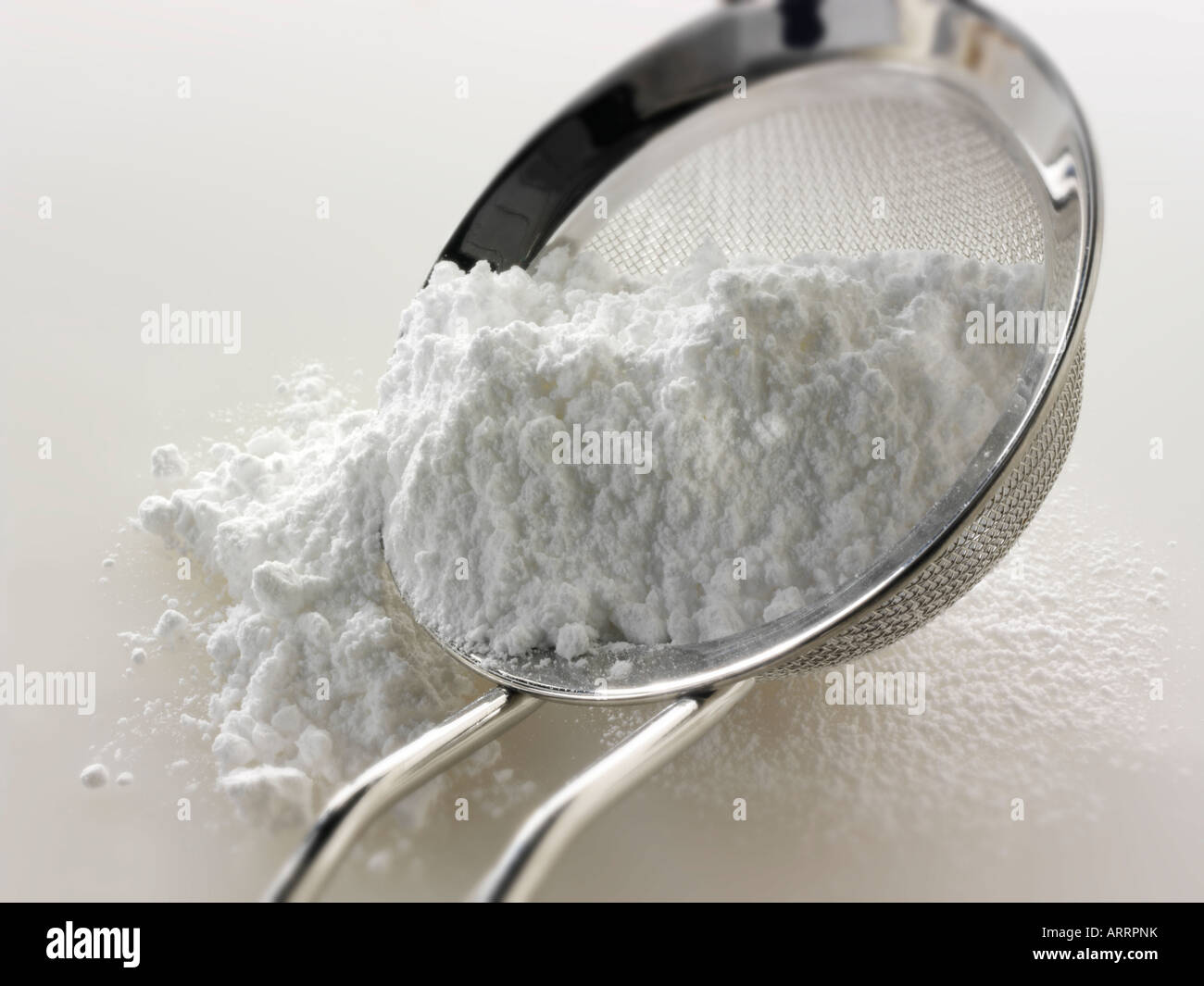 Icing sugar in a sieve against a white background Stock Photo