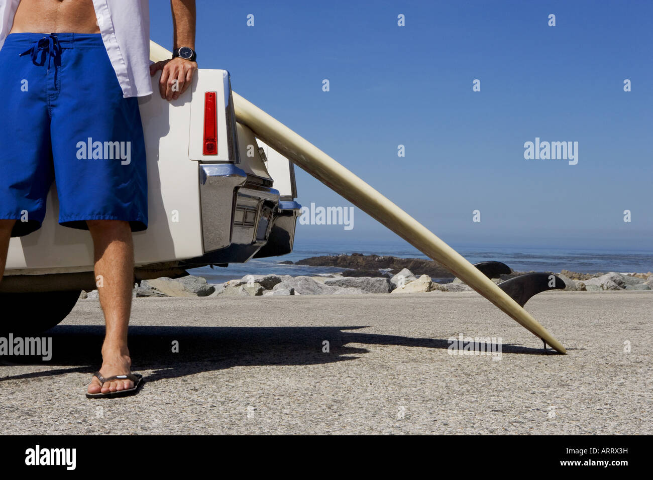 Low angle view of man leaning against car at beach Stock Photo