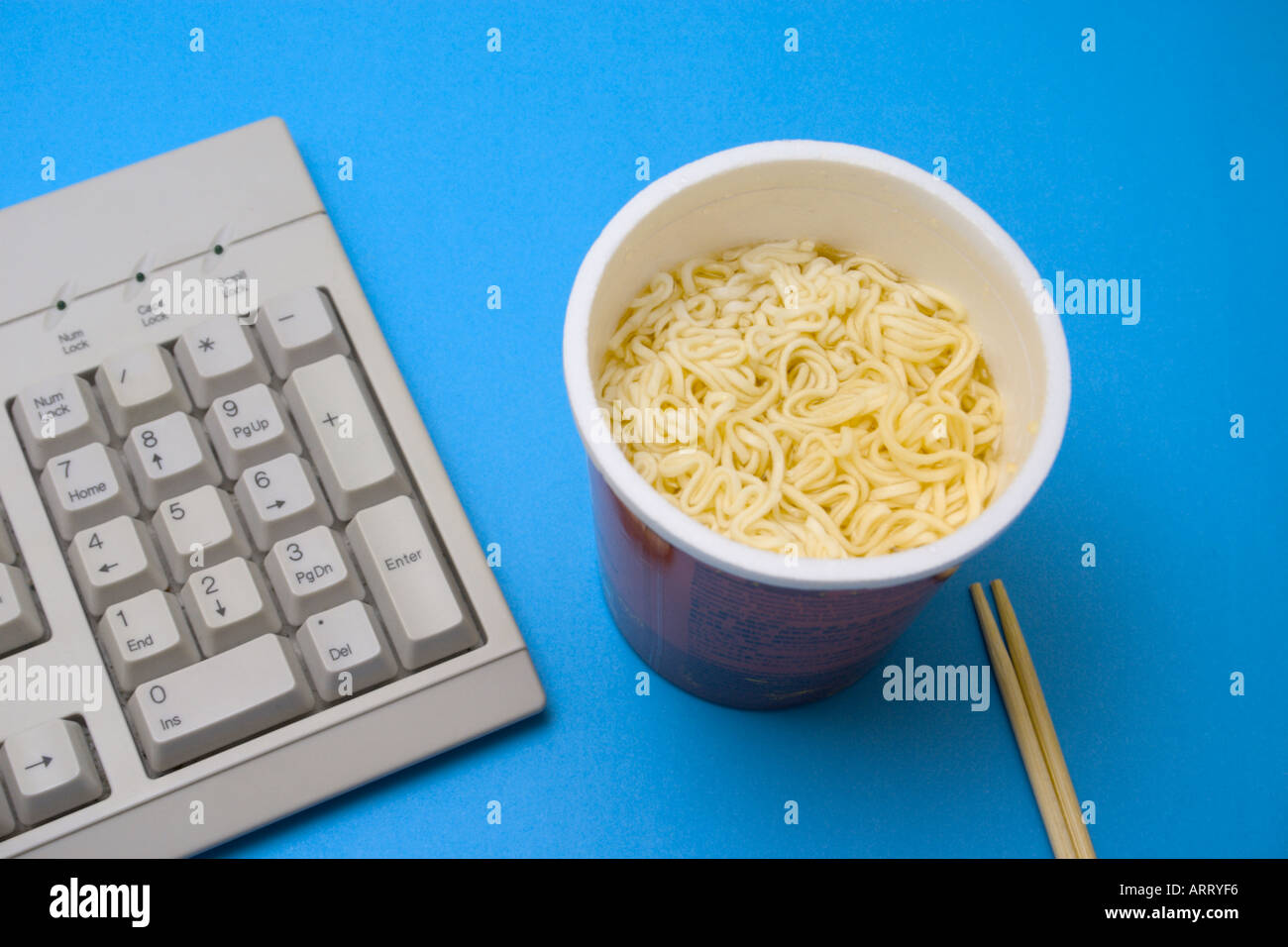 instant noodles cup and chopsticks on table with keyboard Stock Photo