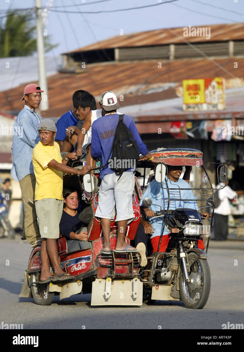 Filipinos ride a tricycle taxi through the streets of Mansalay, Oriental Mindoro, Philippines. Stock Photo