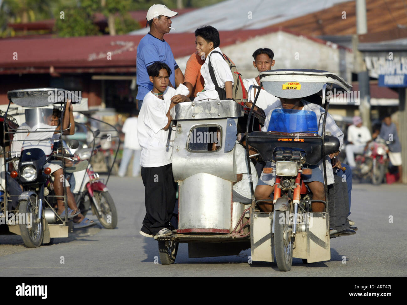 Filipinos ride a tricycle taxi through the streets of Mansalay, Oriental Mindoro, Philippines. Stock Photo