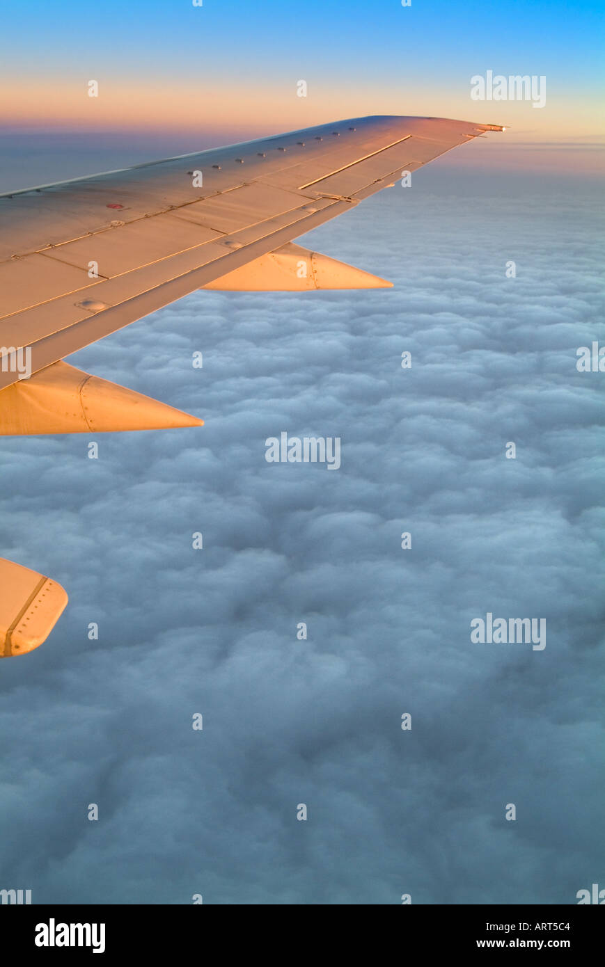 Airplane Jet Wing Flying Above The Clouds At Sunise Stock Photo