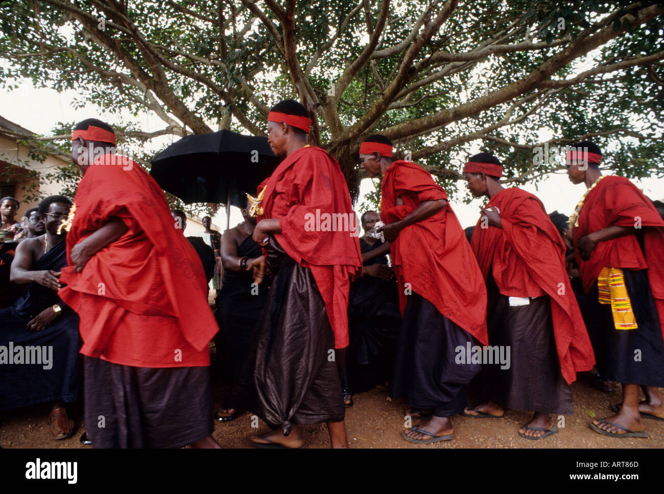 Funeral of a wealthy Ashante man in Kumasi The women wearing red cloth and gold were the wives of the deceased The others wearing red are direct relatives The people wearing black were friends Here The relatives of the deceased Bei der Trauerfeier eines wohlhabenden Mannes aus Kumasi stellt die Familie ihren Reichtum oeffentlich zur Schau Vor allem die Witwen und Kinder legen wertvollen Goldschmuck an Stock Photo