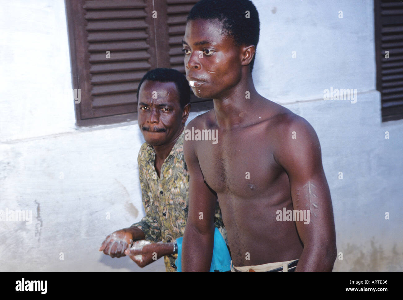 A young man foams from his mouth a sign that Nana Akonodi has entered him An Tagen an denen die Goettin Akonedi auftritt koennen aber auch andere Goetter in die Priesterin und Anwesenden fahren Einem jungen Mann tritt Schaum aus dem Mund ein Zeichen dafuer dass ein Gott ihn besetzt hat In diesem Fall eine Gottheit aus dem Norden zu deren Spezialitaet es gehoert ihre Medien bei der Hexenjagd zu unterstuetzen Stock Photo