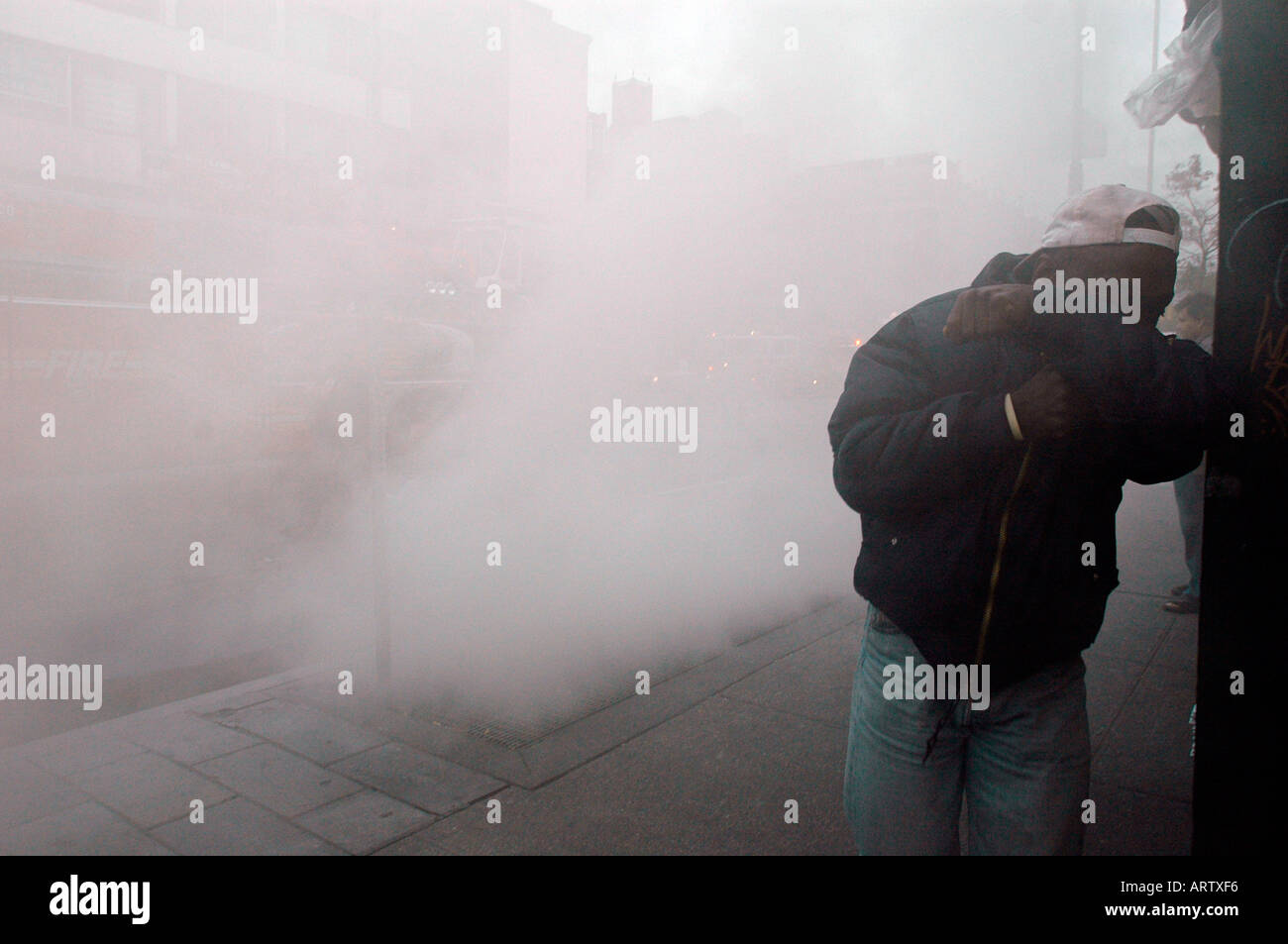 Pedestrians walk through smoke escaping from an underground fire at the West Fourth Street IND subway station in NYC Stock Photo