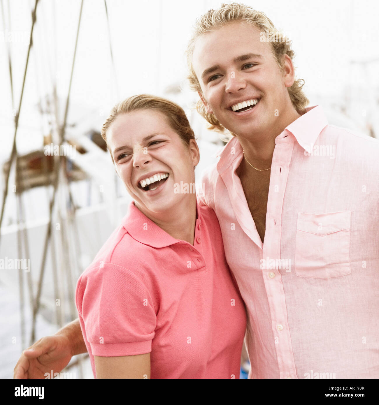Young couple standing with their arms around each other and smiling ...