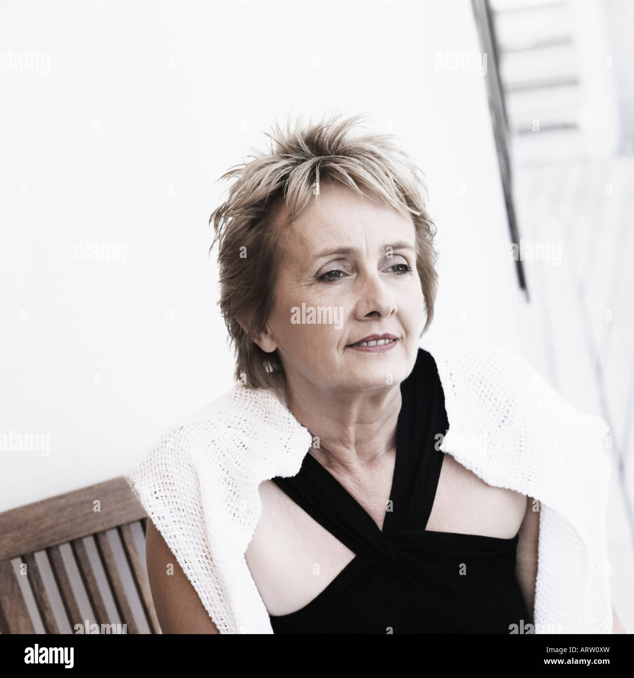 Mature woman sitting on a chair and smiling Stock Photo - Alamy