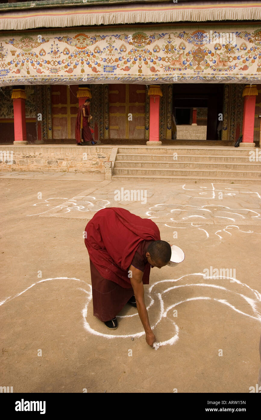 Tibetan monk drawing outlines on the ground in front of the prayer hall at Labrang Monastery, Xiahe. Stock Photo