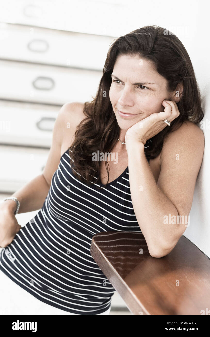 Mid adult woman smirking with her hand on her chin Stock Photo