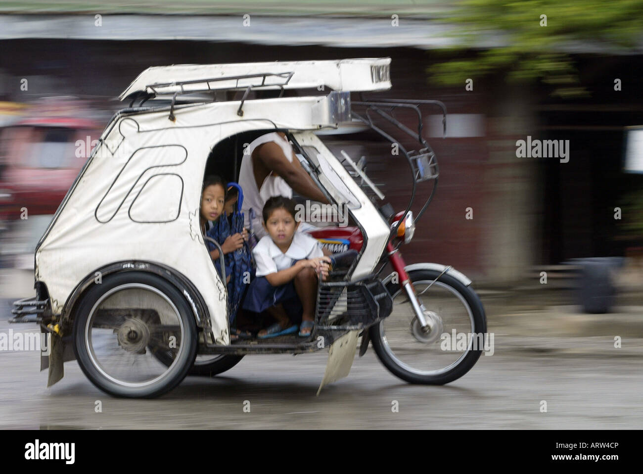 Children ride a tricycle taxi to school in Mansalay, Oriental Mindoro, Philippines. Stock Photo