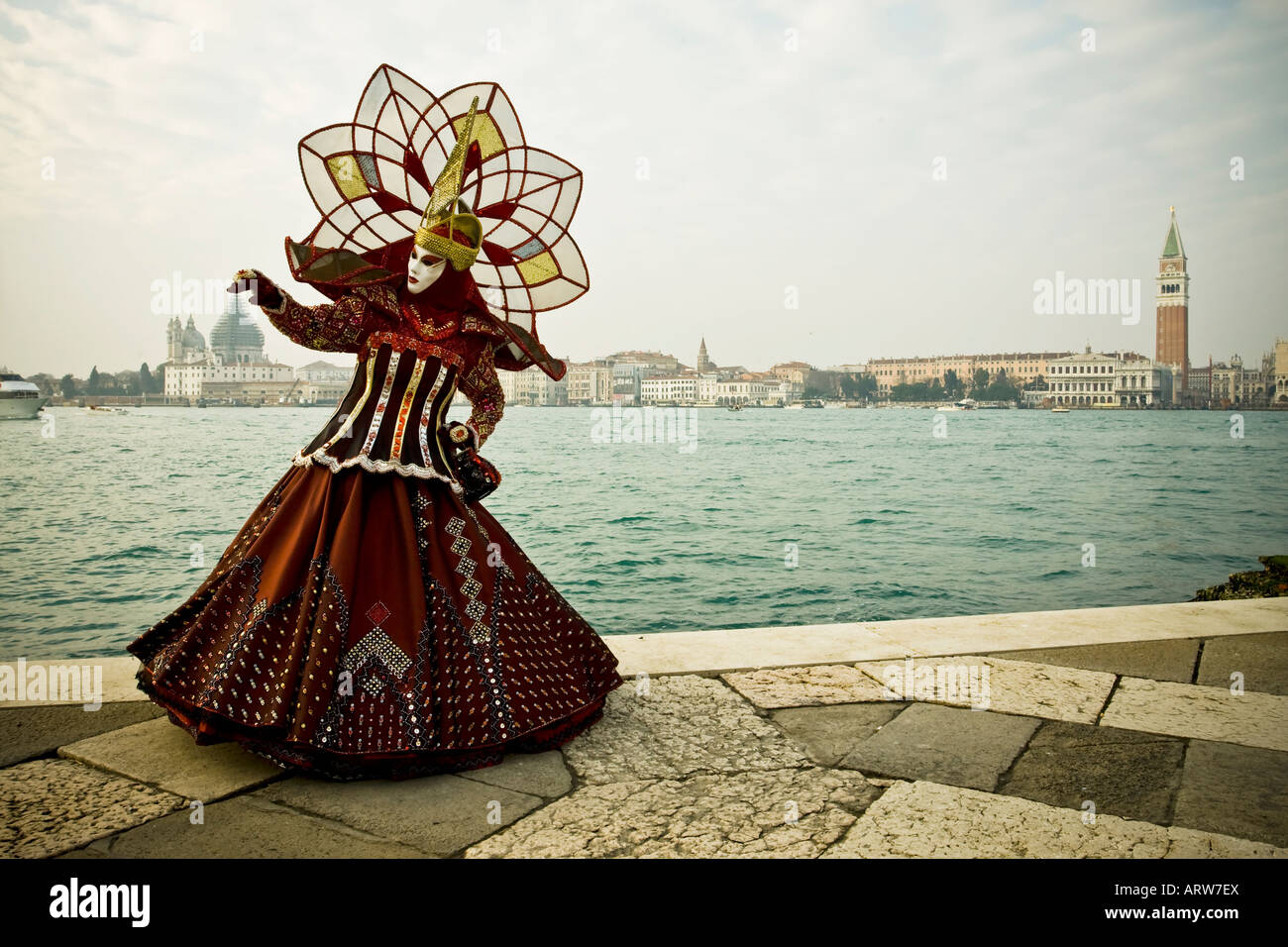 A woman dressed in costume and mask attending the Venice Carnival Venice Italy poses on San Giorgio Maggiore Stock Photo