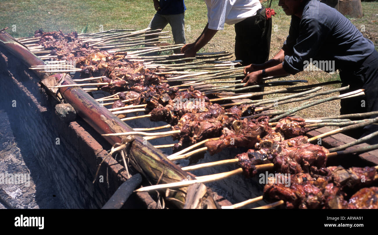 Paraguayan men preparing meat on skewers over a parrilla a barbeque an open fire pit near Trinidad and Jesus Paraguay Stock Photo