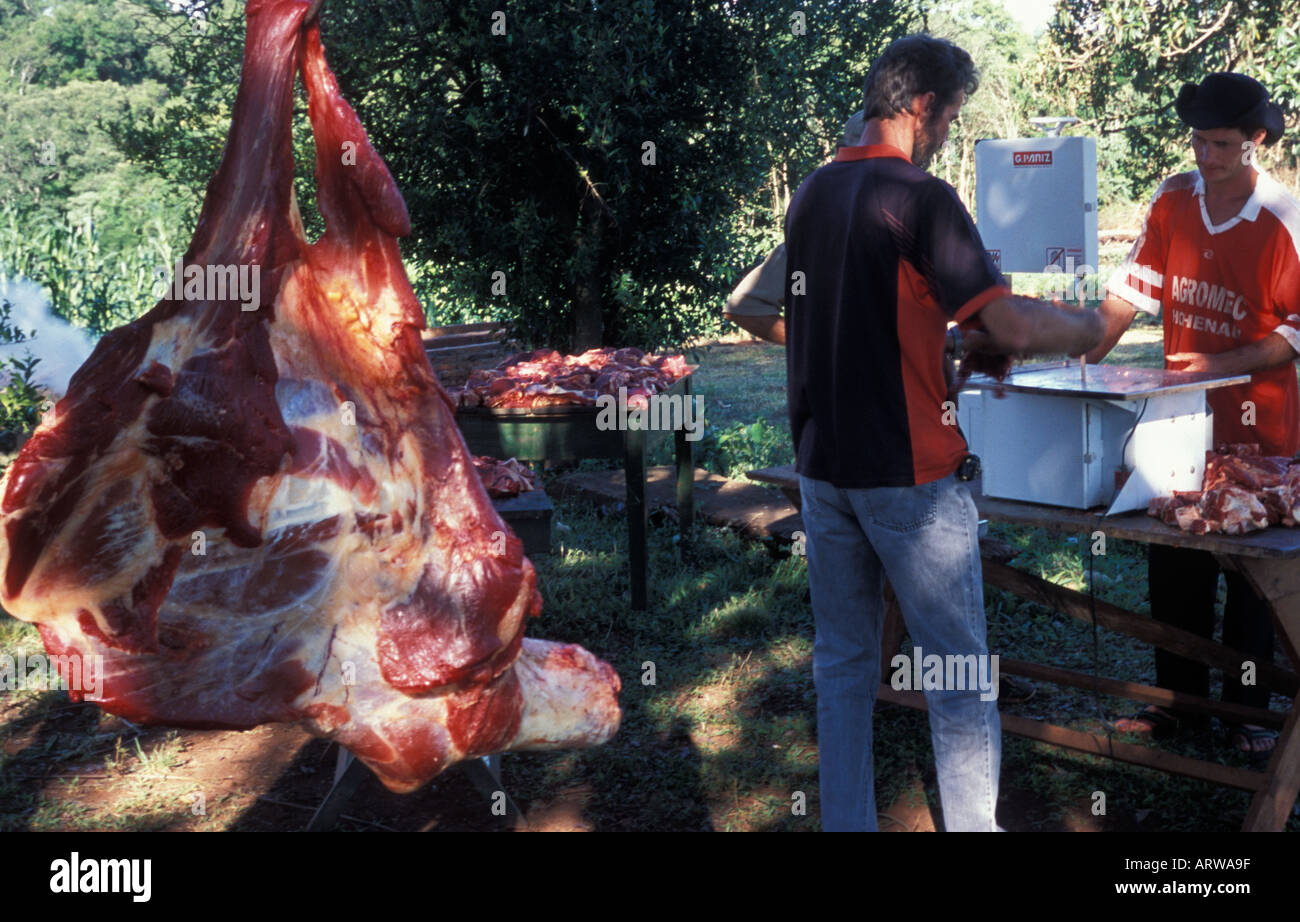 Paraguayan men cutting meat for a parrilla a barbeque an open fire pit near Trinidad and Jesus Paraguay Stock Photo