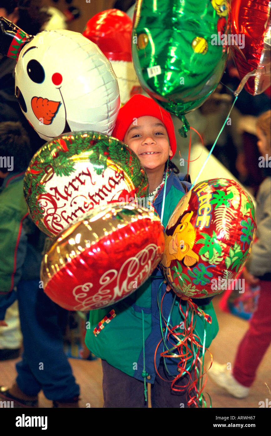 Boy age 6 surrounded by balloons at soup kitchen Christmas party