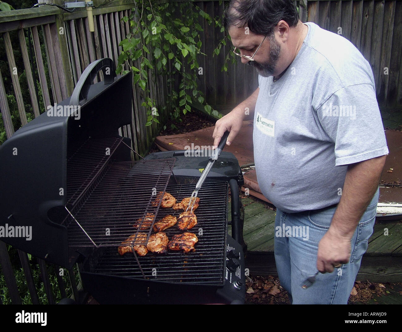 man grilling chicken on barbeque grill Stock Photo - Alamy