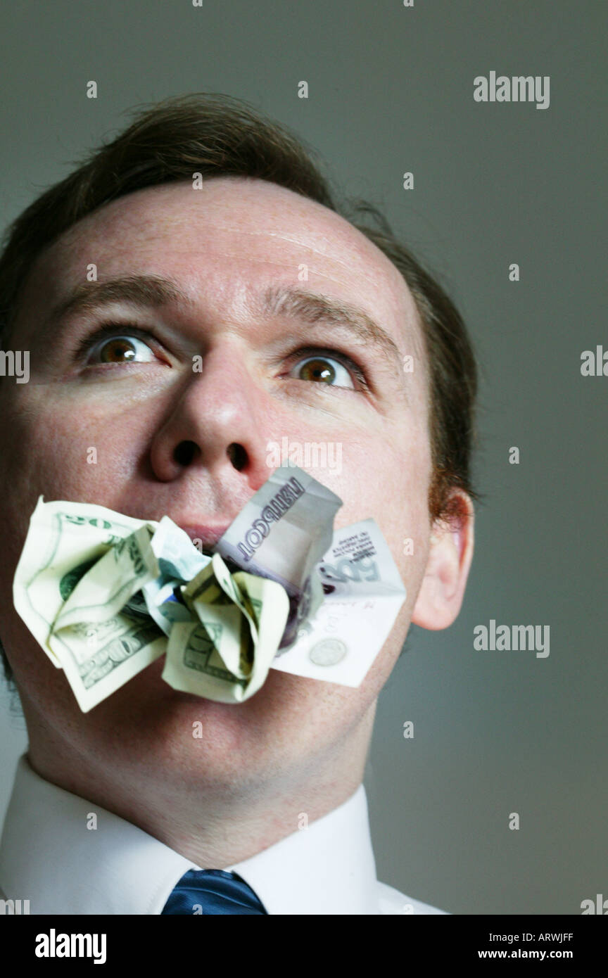 Man with money stuffed in his mouth Stock Photo