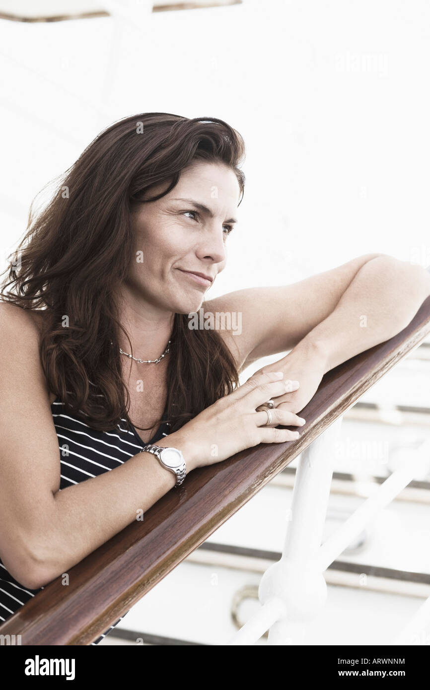 Close-up of a mid adult woman leaning against a banister and smirking Stock Photo