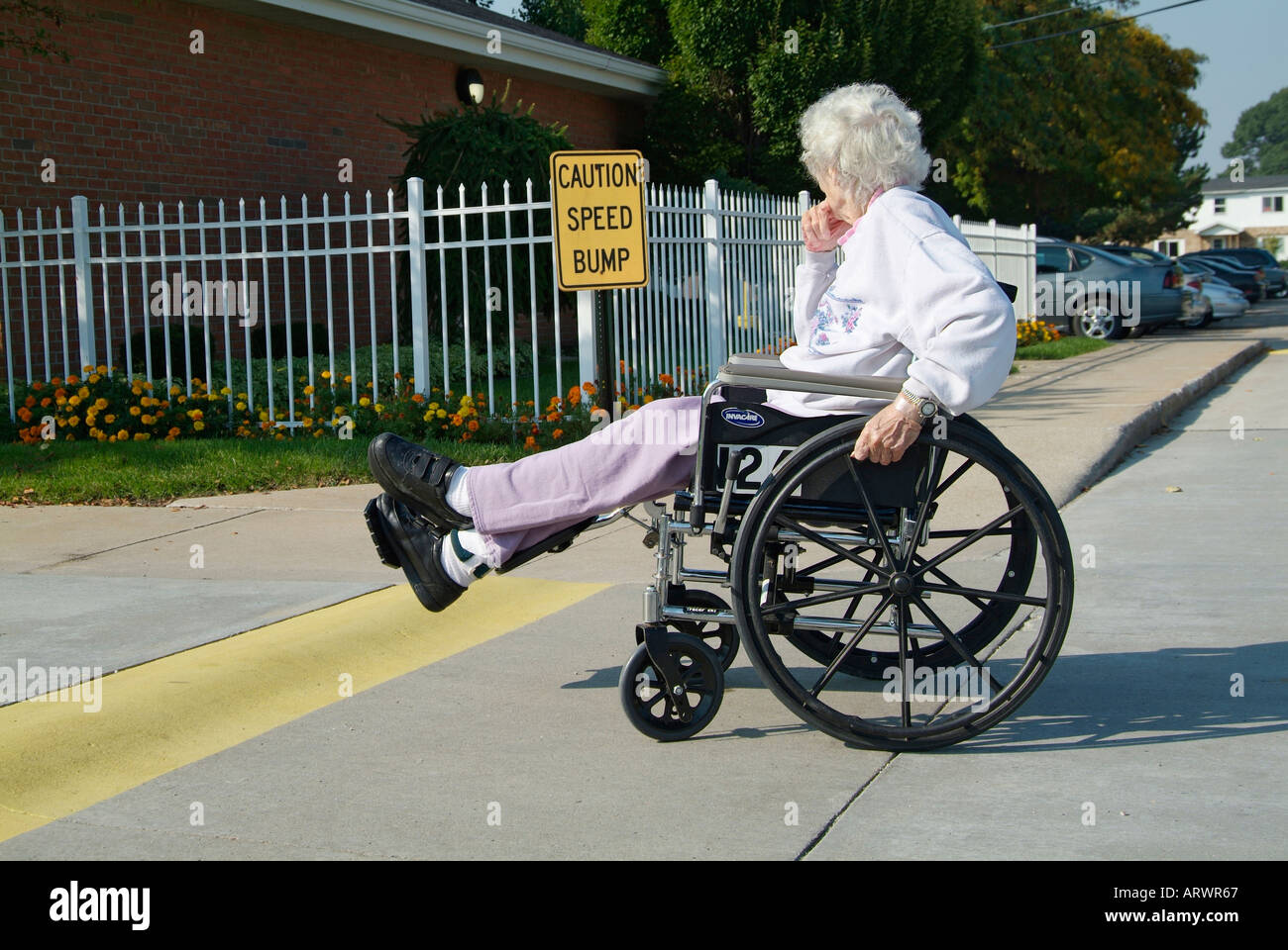 Senior female in a wheelchair try's to overcome an obstacle in a speed bump on a street Stock Photo