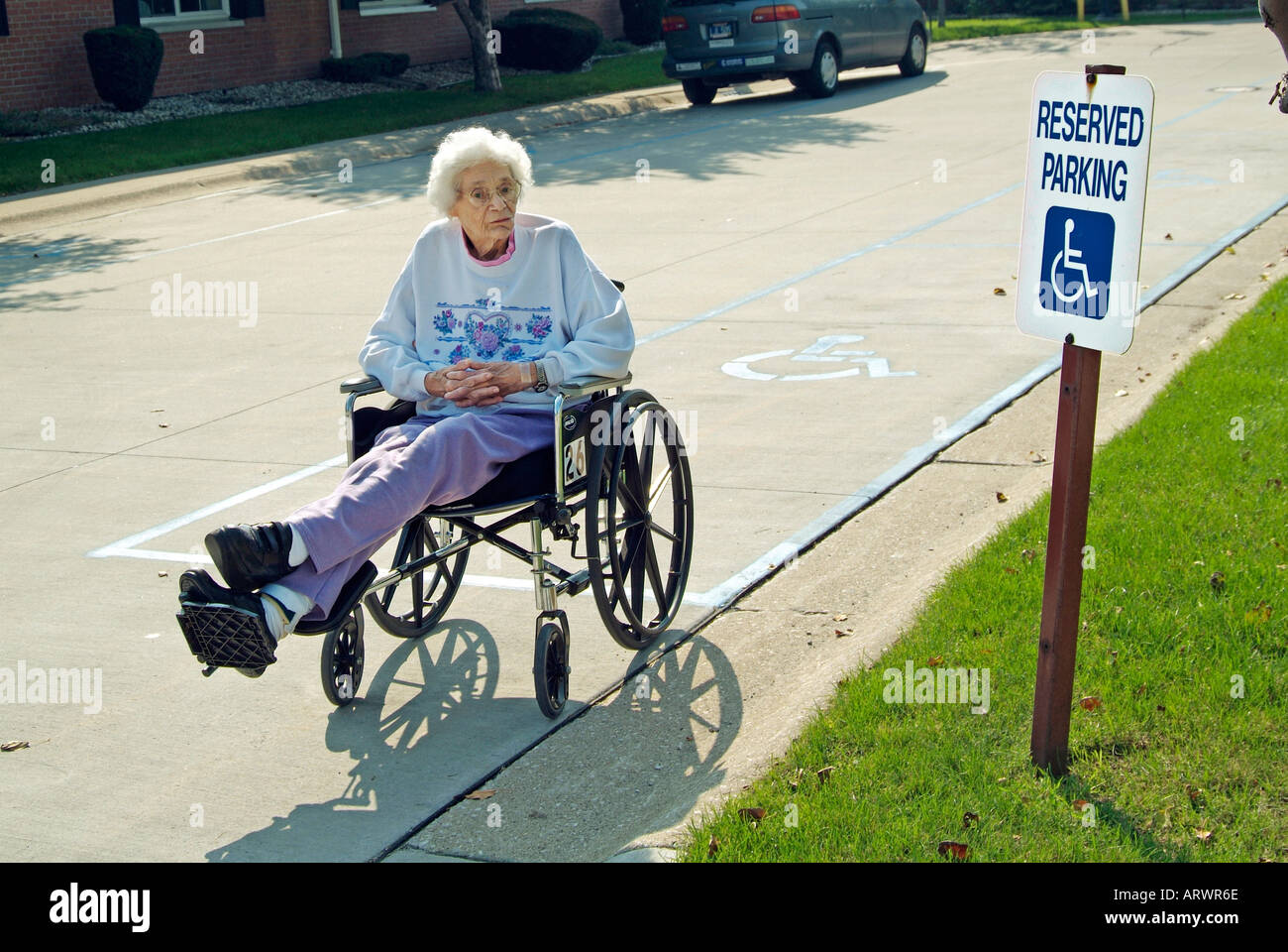 Senior female in a wheelchair try's to overcome an obstacle in a speed bump on a street Stock Photo