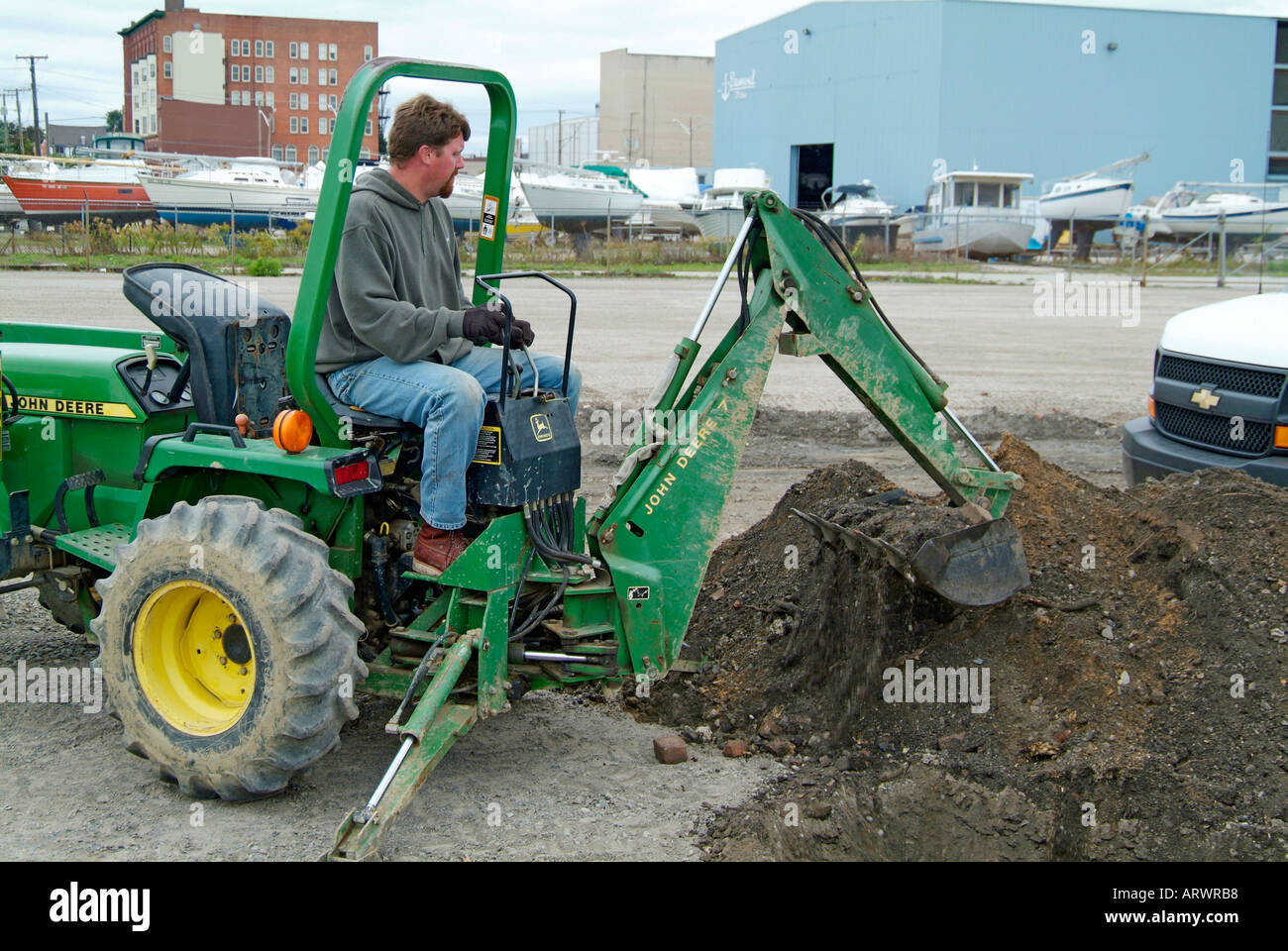 Man Using Backhoe Adult male construction worker uses back hoe to dig a trench to lay ...