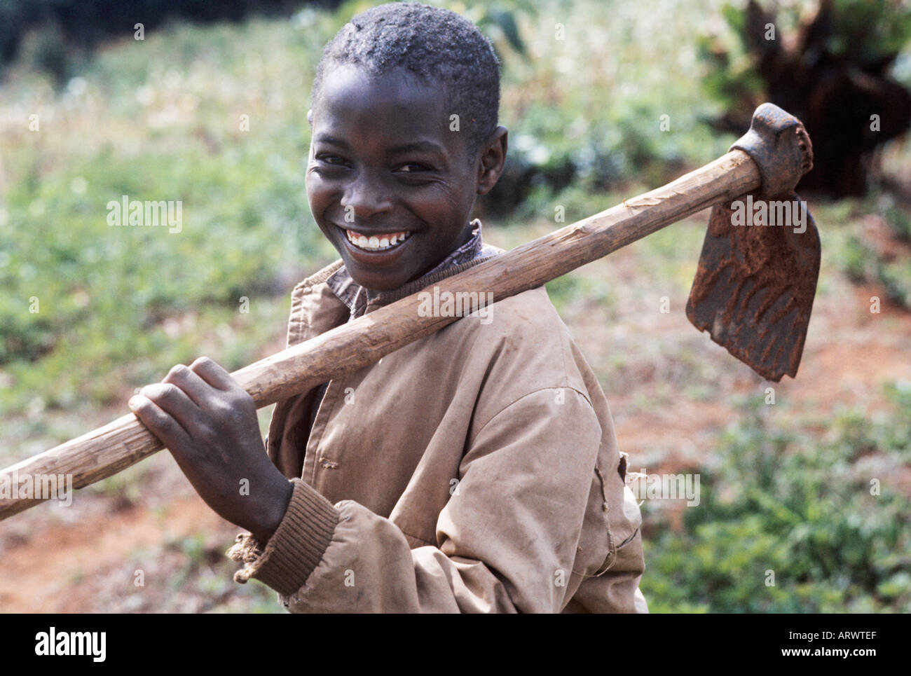 A brighteyed boy from a Kikuyu rural family near Nairobi, Kenya, ready with his hoe to work on the family farm Stock Photo