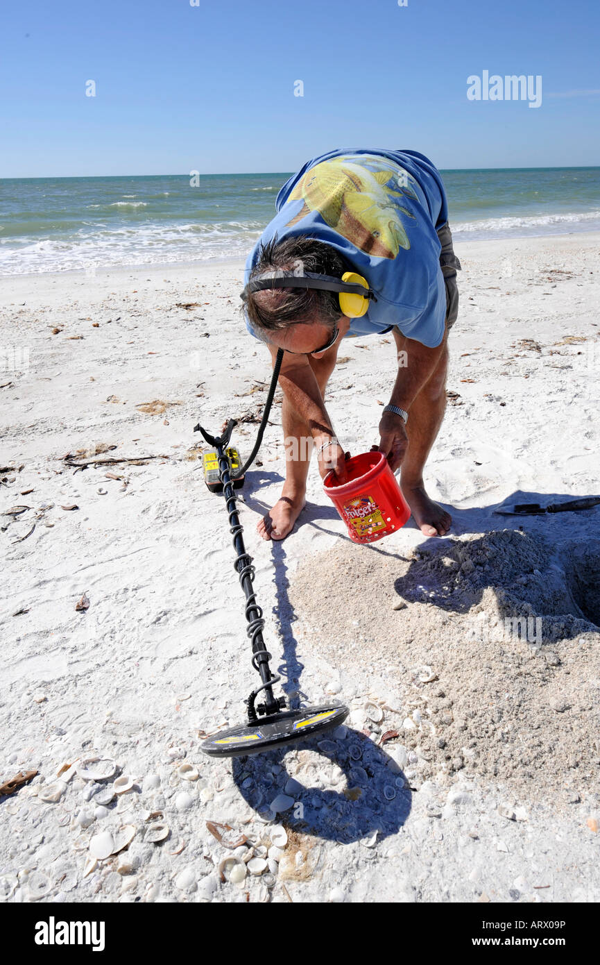 Senior male uses metal detector to find objects on a beach at Naples ...