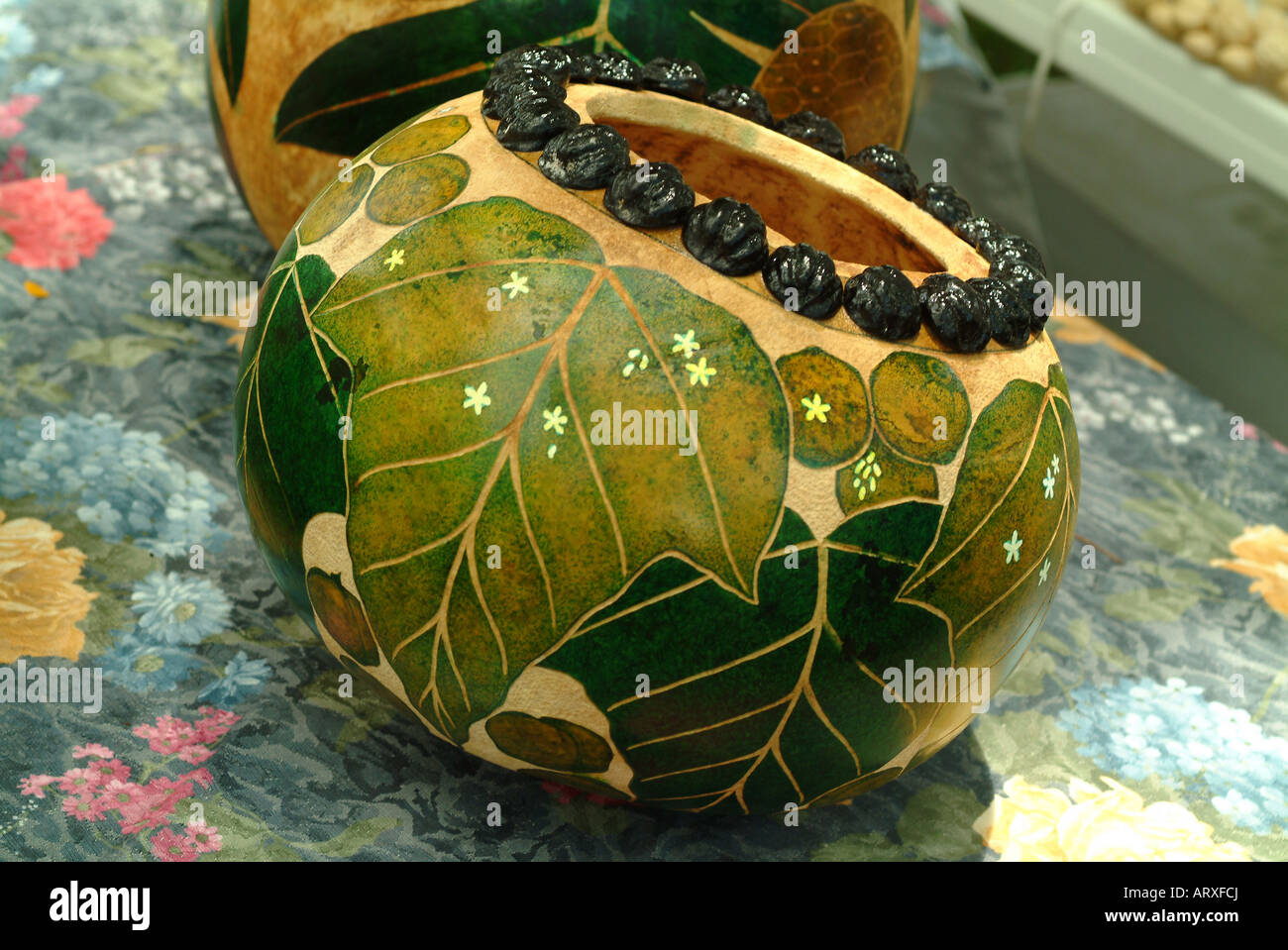 Hawaiian bowl or gourd with an intricate leaf design and kukui nuts at