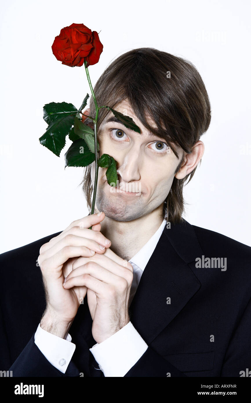 studio shot portrait of a young funny expressive thin and tall man on isolated background holding a rose Stock Photo