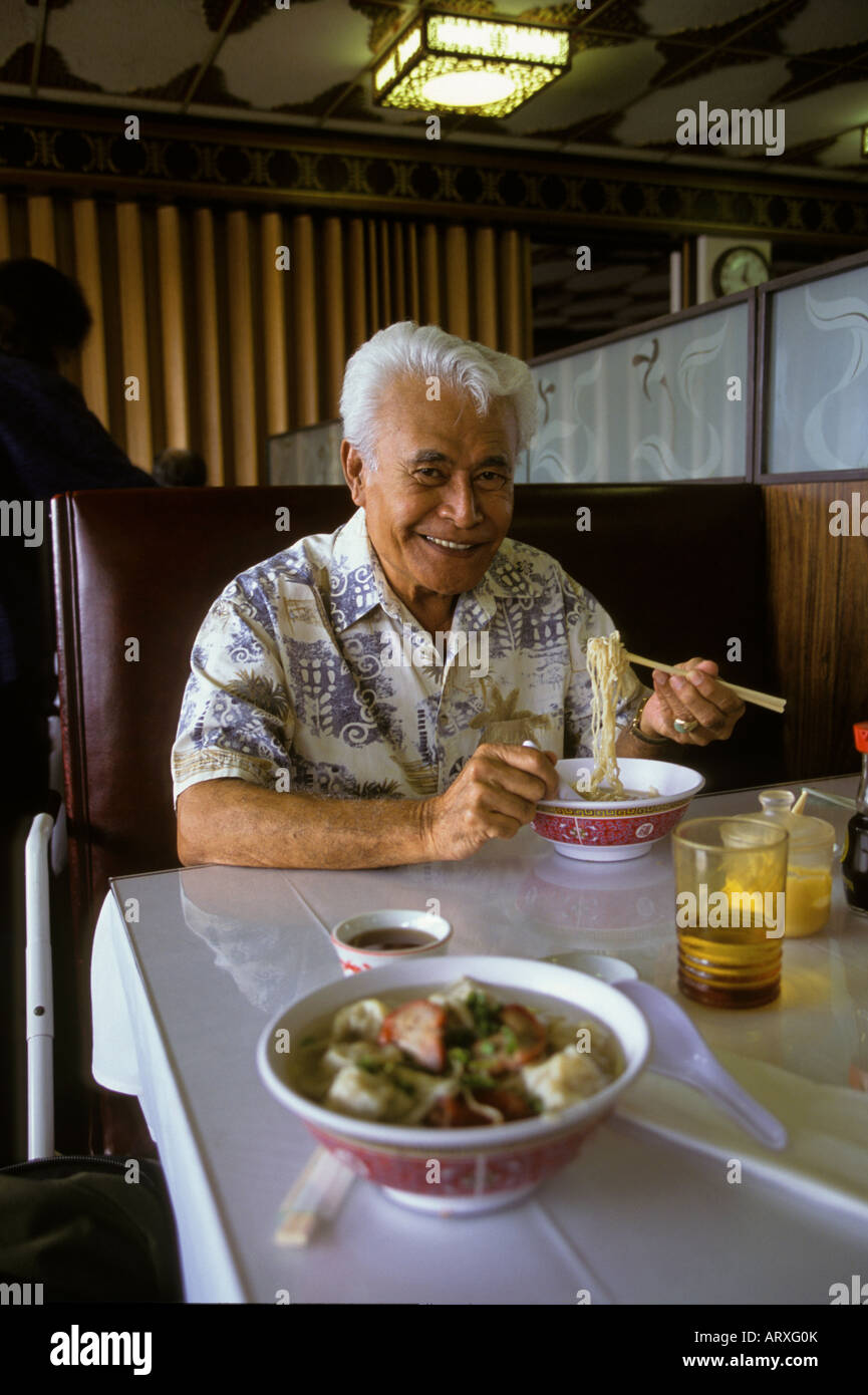 Hawaiian man in restaurant eating wo gau gee mein (dumplings, pork, shrimp, vegetables, noodles); Kaneohe, Windward Oahu Stock Photo
