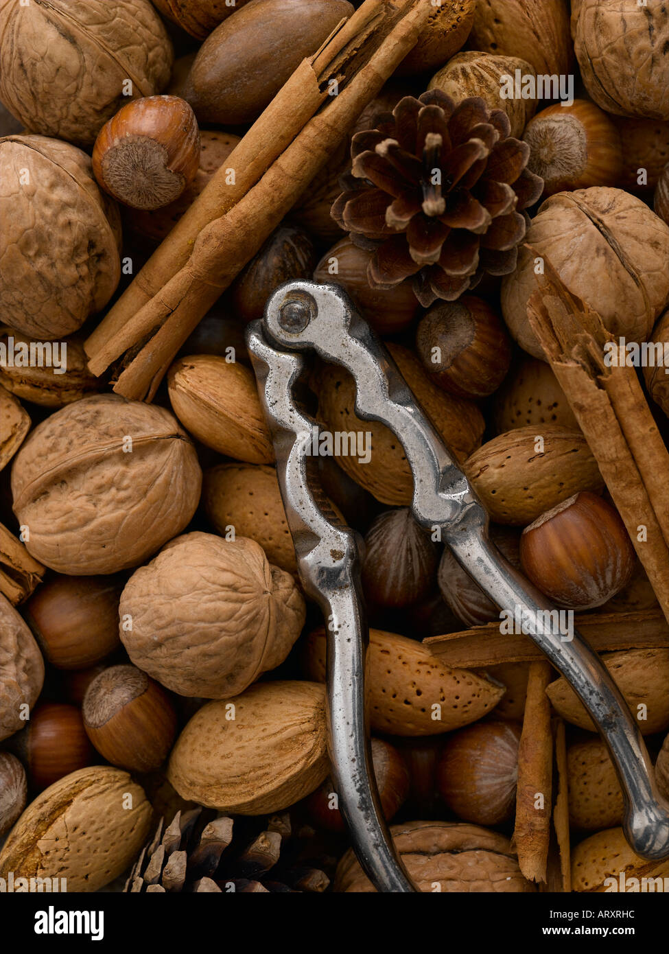 Mixed nuts pine cones nut crackers and cinnamon quills Stock Photo Alamy
