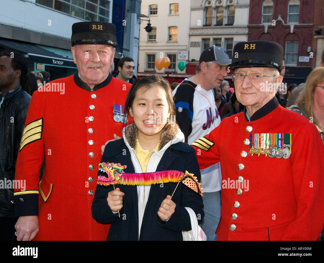 A Korean tourist in London at the Chinese New Year posing for photographs with two Chelsea pensioners Stock Photo