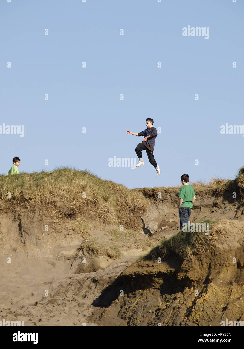 Boys jumping the gaps in sand dunes Stock Photo Alamy