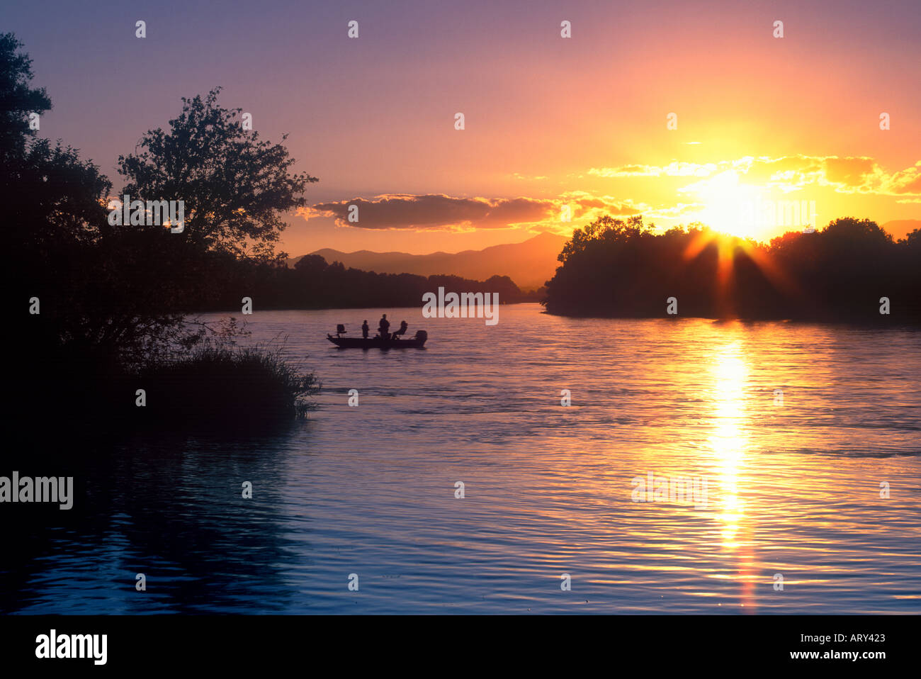 Boaters float down the Sacramento River at sunset Stock Photo