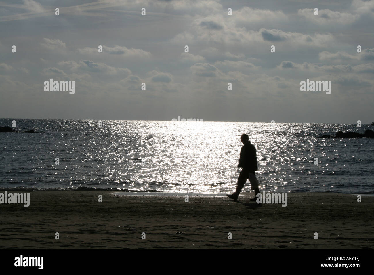 man walking along beach Stock Photo - Alamy